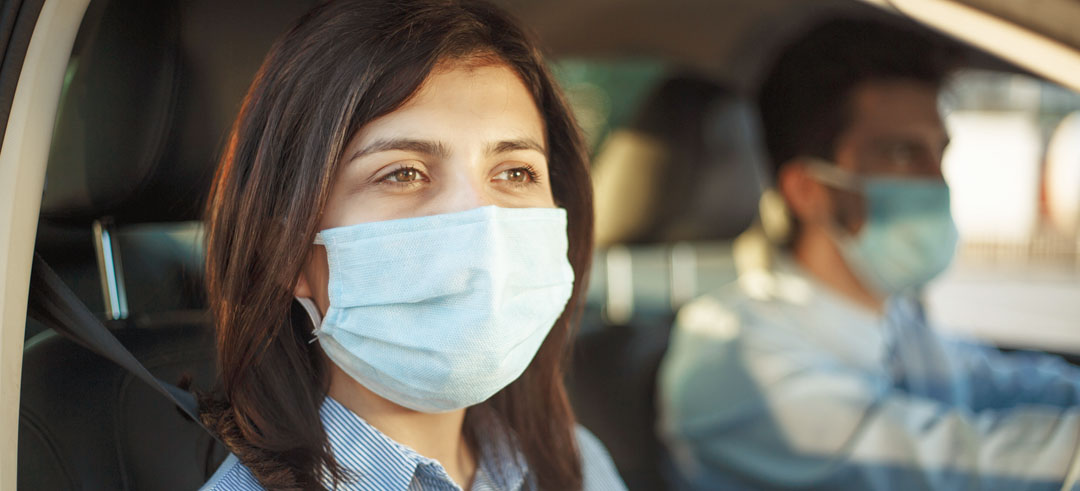 Dos personas con mascarilla en el interior de un coche