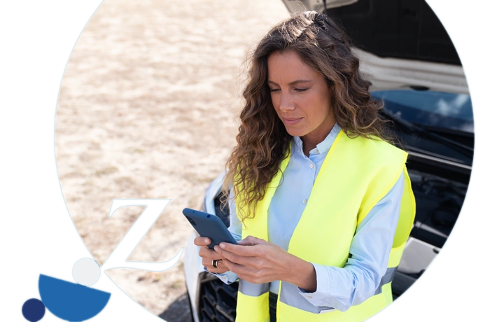 chica con chaleco reflectante y capó del coche levantado escribiendo en el móvil