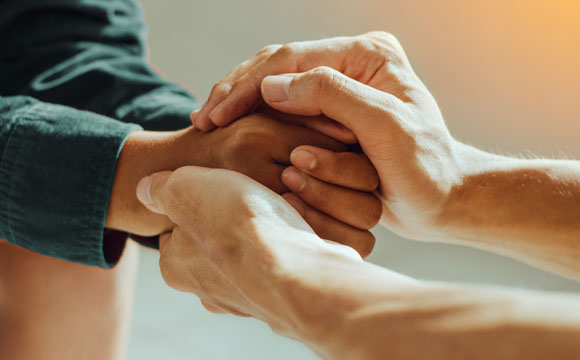 una persona cogiéndole las manos a otra